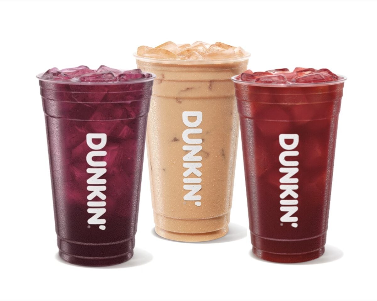 Three Dunkin' Halloween drinks over ice in clear cups: the Midnight Potion and Werewolf Punch Refreshers in deep purple and red, with the creamy tan Nutty Nightmare Iced Coffee between them